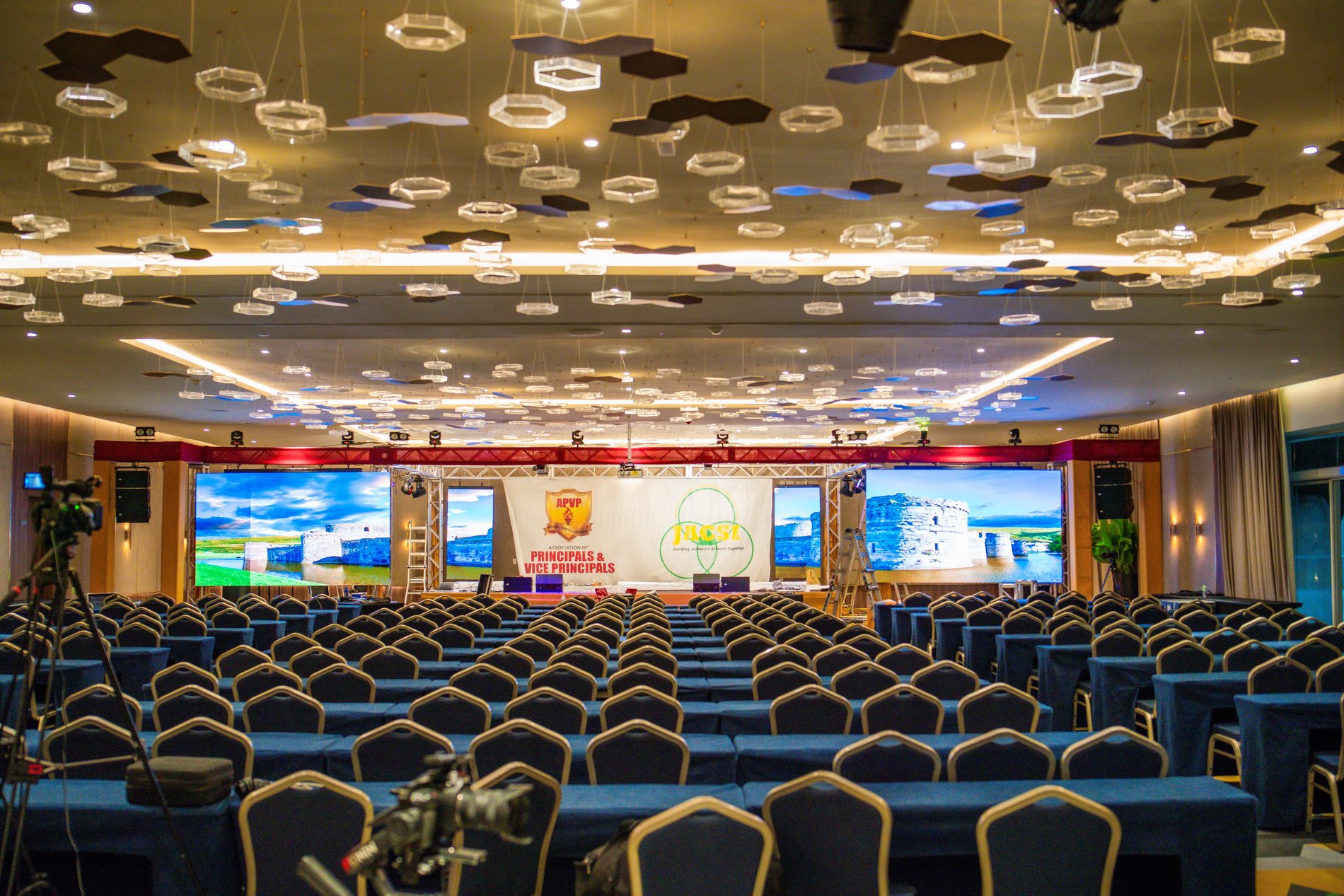 The same ballroom fully built, with LED screens lit and the stage dressed