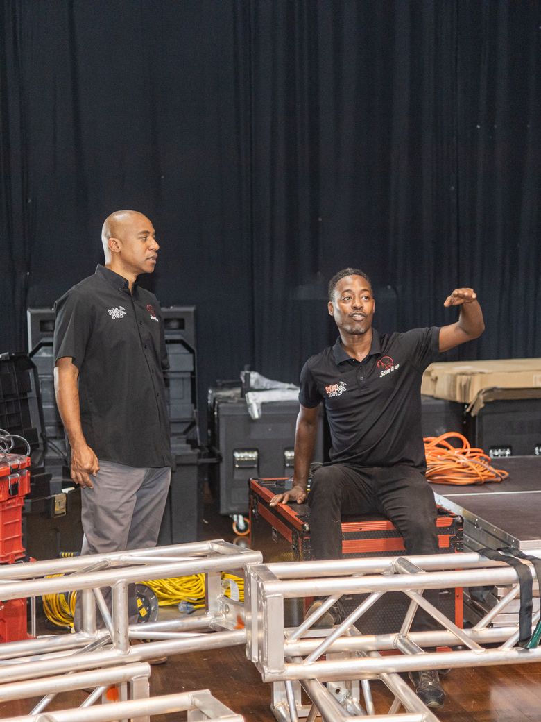 Two Sound It Up crew members planning the build on the stage deck