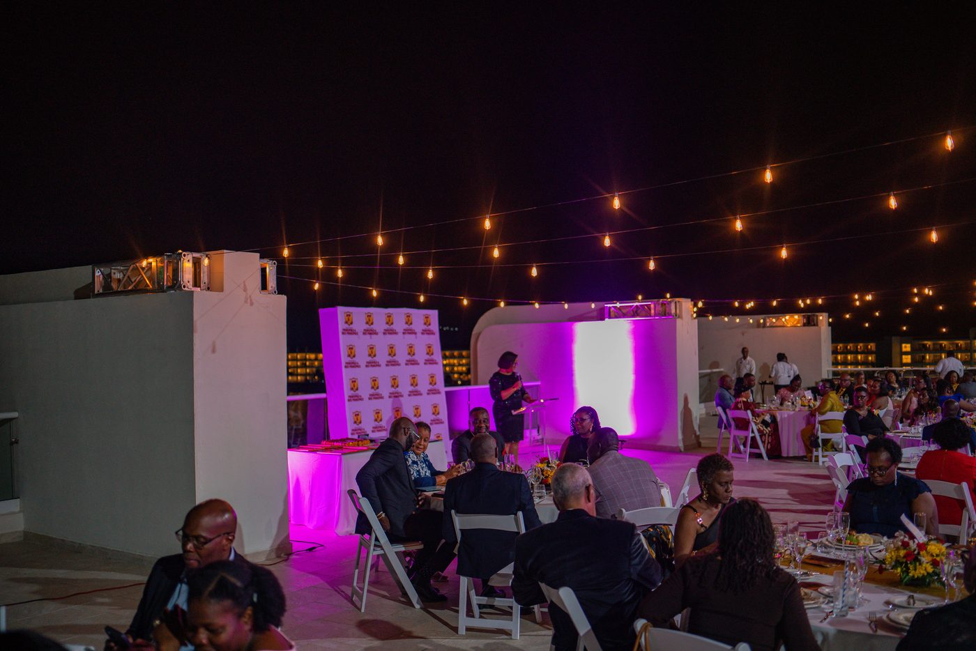 Rooftop dinner under festoon lights with uplit walls and dressed tables