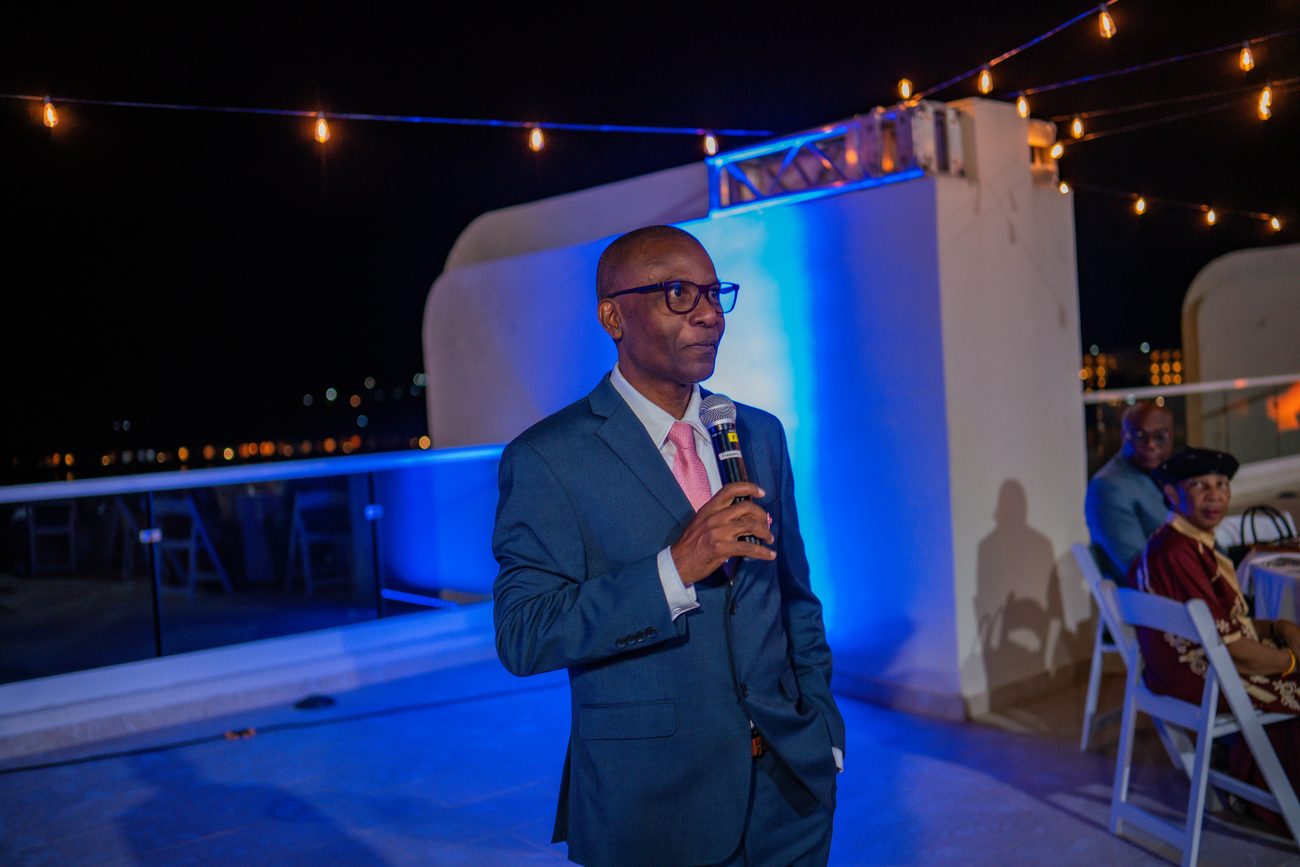 Rooftop event with a speaker under blue uplighting overlooking the sea